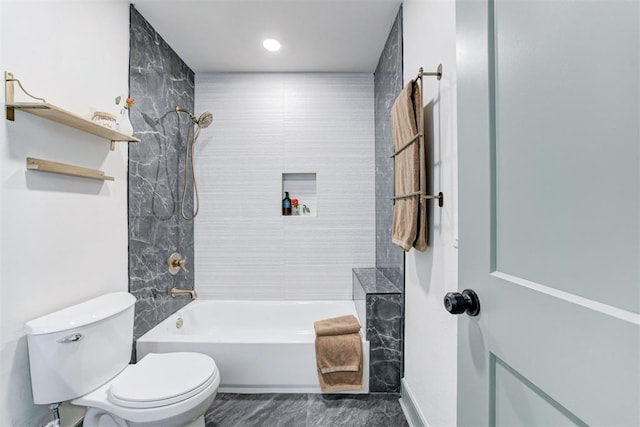 bathroom featuring tiled shower / bath combo and toilet