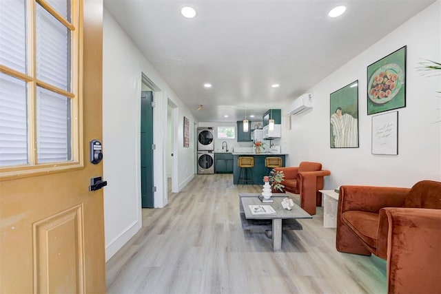 living room featuring stacked washer and clothes dryer, a wall mounted AC, and light wood-type flooring