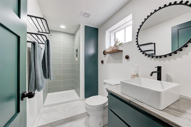 bathroom with vanity, toilet, and a tile shower