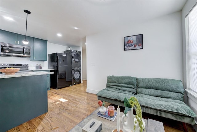 living room with light hardwood / wood-style flooring and stacked washer / dryer