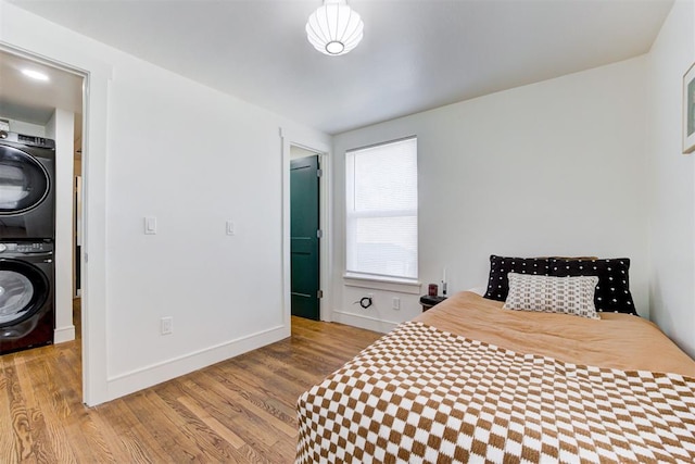 bedroom featuring stacked washer / dryer and light hardwood / wood-style flooring