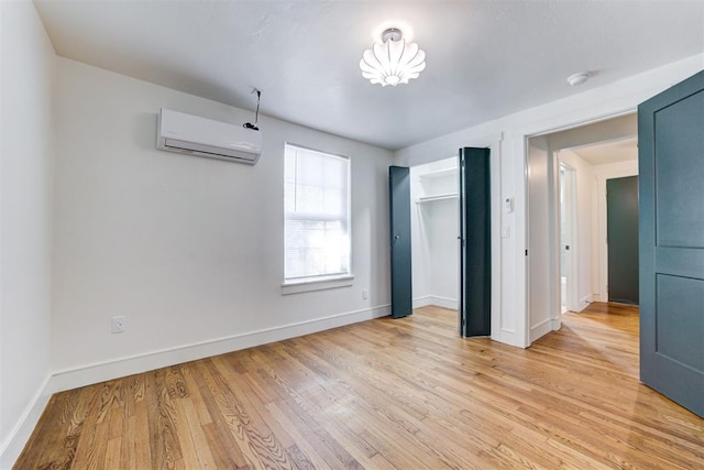 unfurnished bedroom featuring a wall unit AC, a closet, and light wood-type flooring