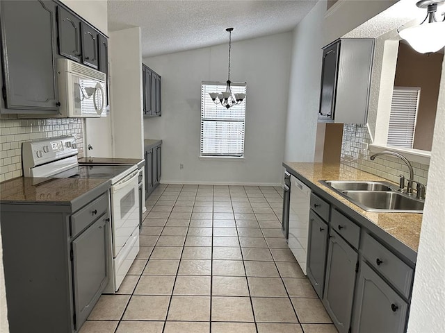 kitchen with white appliances, gray cabinets, vaulted ceiling, and sink