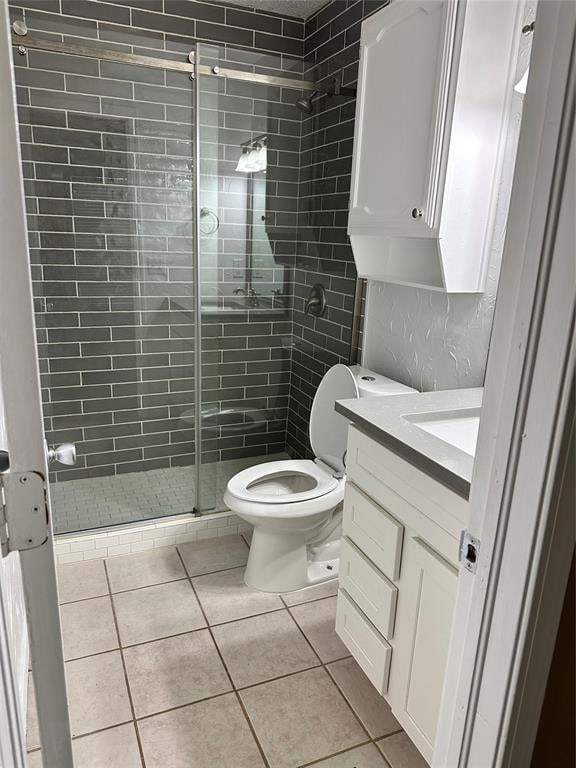 bathroom featuring tile patterned floors, vanity, an enclosed shower, and toilet