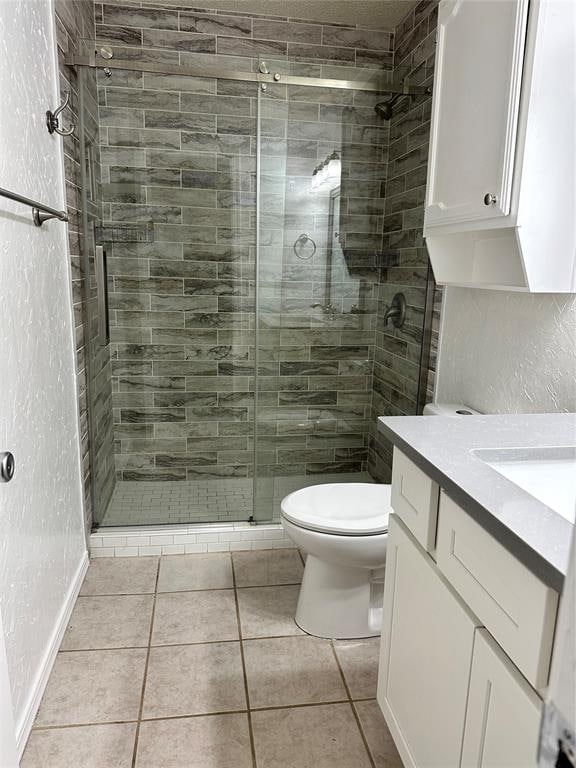 bathroom featuring tile patterned flooring, vanity, toilet, and an enclosed shower