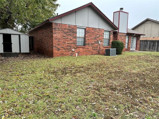 rear view of house featuring central AC, a shed, and a lawn