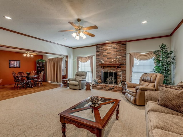 living room with crown molding, a brick fireplace, hardwood / wood-style flooring, ceiling fan, and a textured ceiling