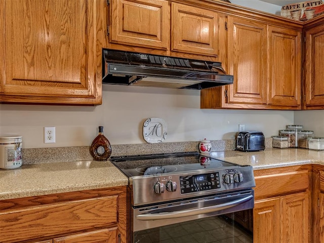 kitchen with light stone countertops and stainless steel range with electric stovetop