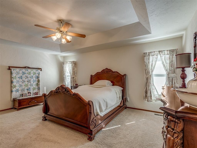 bedroom featuring carpet flooring, a raised ceiling, and ceiling fan