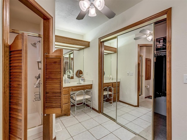 bathroom featuring vanity, a shower with door, tile patterned floors, ceiling fan, and a textured ceiling