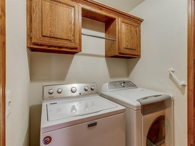 laundry room with washing machine and clothes dryer and cabinets