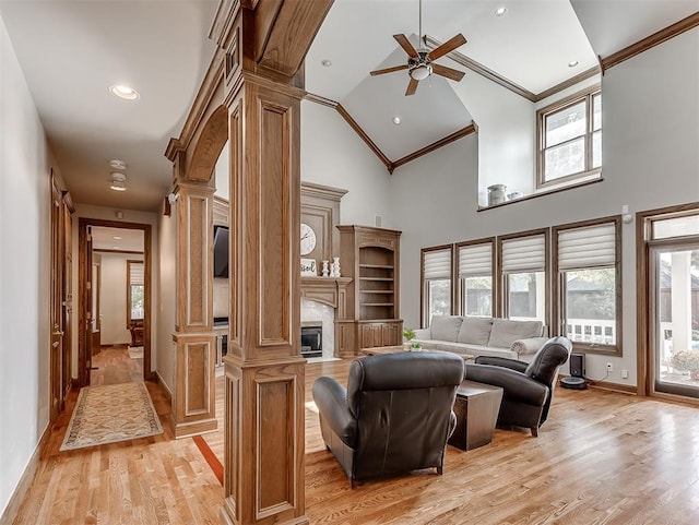 living room with ornate columns, ornamental molding, ceiling fan, high vaulted ceiling, and light hardwood / wood-style floors