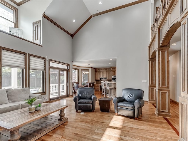 living room with high vaulted ceiling, light hardwood / wood-style flooring, a wealth of natural light, and decorative columns