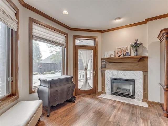 sitting room featuring light wood-type flooring, crown molding, and a premium fireplace