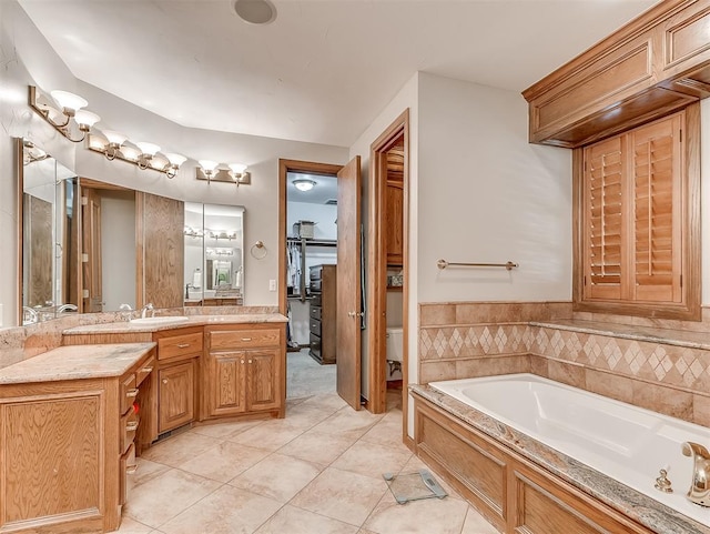 bathroom featuring tile patterned floors, a washtub, toilet, and vanity