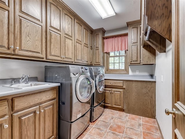 washroom featuring washing machine and dryer, sink, light tile patterned floors, and cabinets