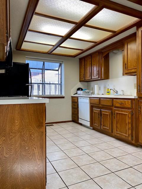 kitchen with black refrigerator, white dishwasher, light tile patterned floors, and sink