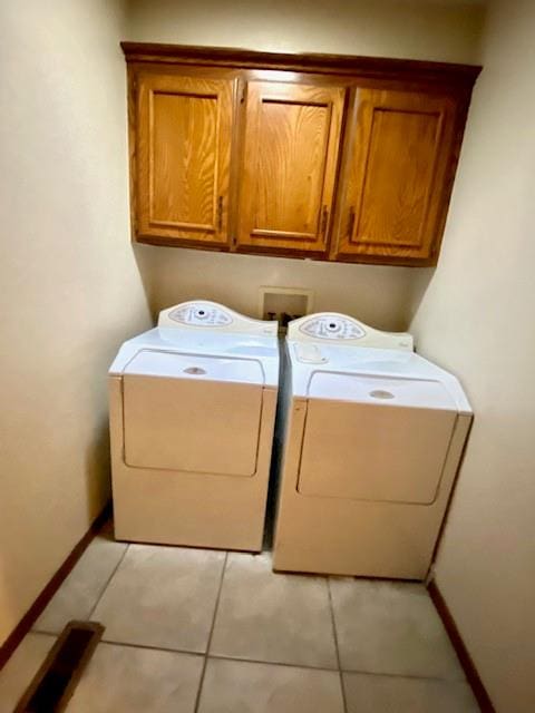 laundry area featuring cabinets, independent washer and dryer, and light tile patterned floors