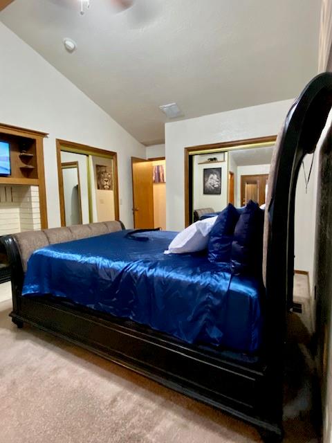 carpeted bedroom with lofted ceiling