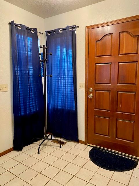 foyer entrance featuring light tile patterned floors and a textured ceiling