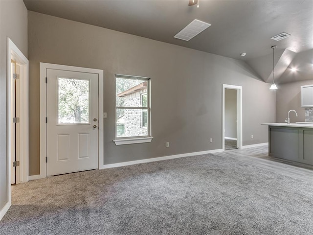 unfurnished living room featuring sink, lofted ceiling, and light carpet