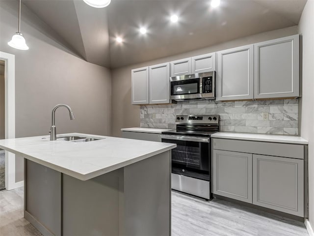 kitchen with gray cabinetry, a center island with sink, sink, appliances with stainless steel finishes, and decorative light fixtures