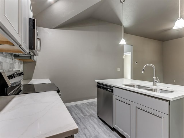 kitchen featuring stainless steel appliances, light hardwood / wood-style flooring, hanging light fixtures, and sink