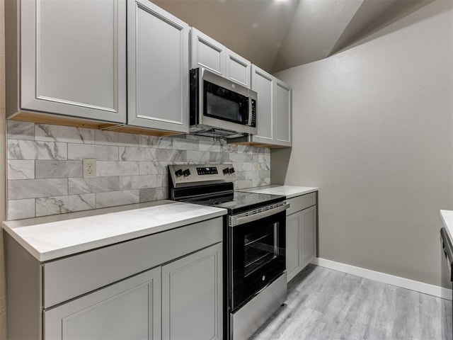 kitchen with light wood-type flooring, stainless steel appliances, and tasteful backsplash