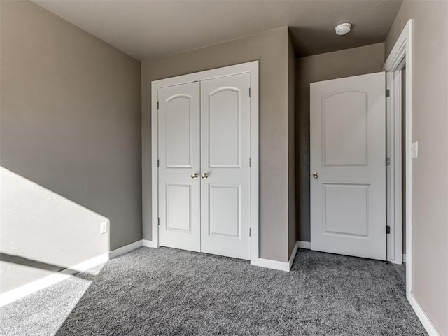 unfurnished bedroom with a closet and dark carpet