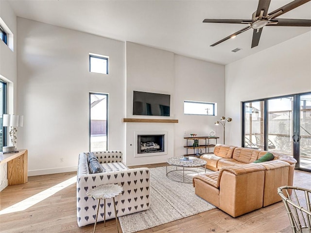 living room with a high ceiling, light hardwood / wood-style floors, and ceiling fan