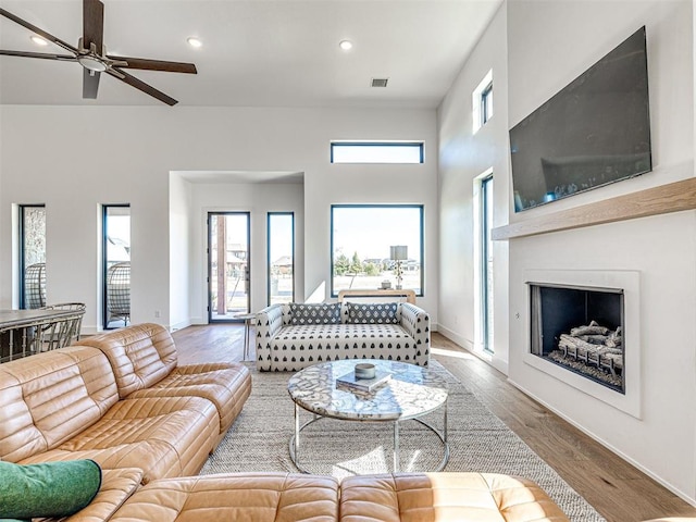 living room featuring hardwood / wood-style floors, ceiling fan, and a high ceiling