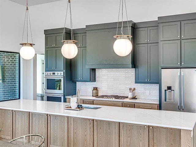 kitchen featuring decorative backsplash, light stone counters, a kitchen island with sink, and appliances with stainless steel finishes