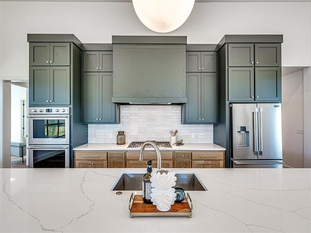 kitchen with backsplash, light stone countertops, ventilation hood, and appliances with stainless steel finishes