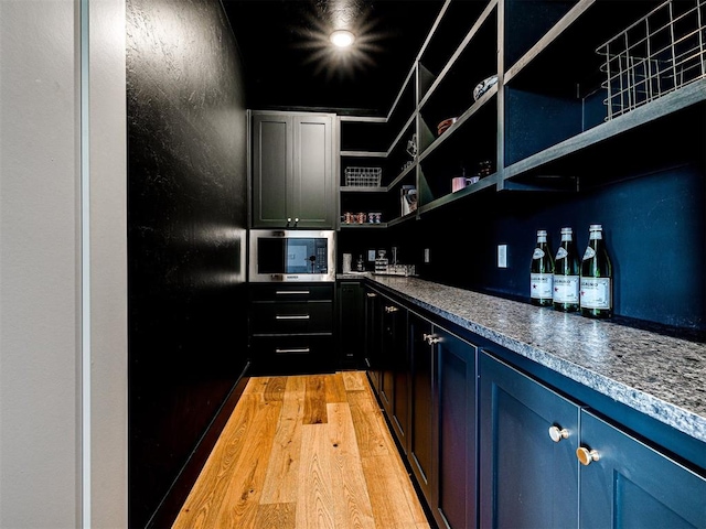 bar featuring light hardwood / wood-style floors and blue cabinets