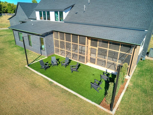 rear view of property featuring a yard and a sunroom