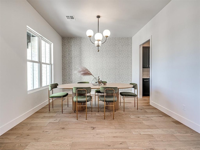 dining room featuring an inviting chandelier, a healthy amount of sunlight, and light wood-type flooring