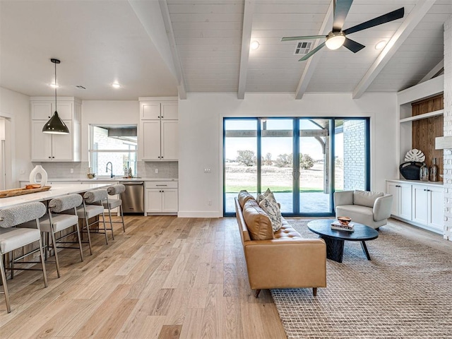 living room with vaulted ceiling with beams, ceiling fan, and light hardwood / wood-style floors