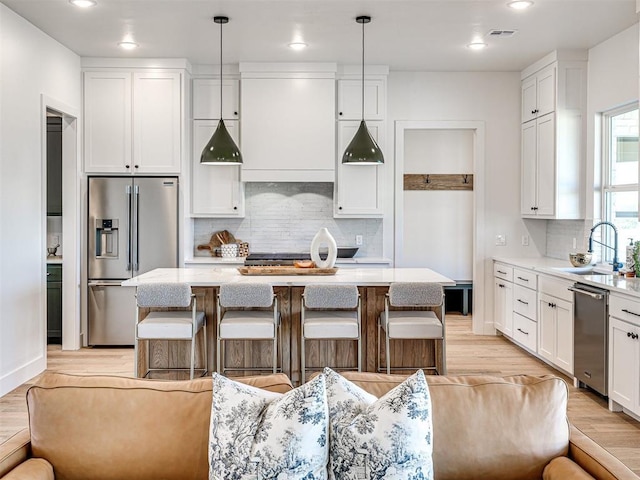 kitchen with decorative light fixtures, a kitchen island, and appliances with stainless steel finishes