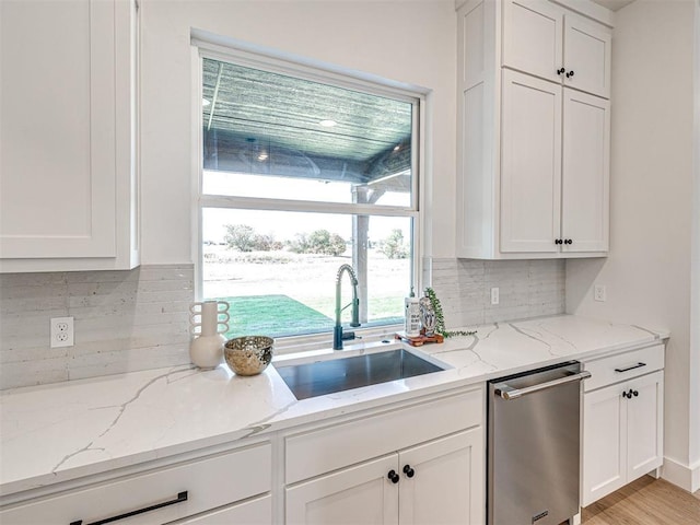 kitchen featuring stainless steel dishwasher, backsplash, light stone countertops, and sink