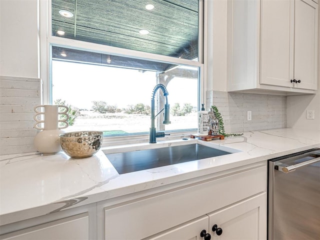 kitchen with white cabinetry, light stone countertops, dishwasher, sink, and tasteful backsplash