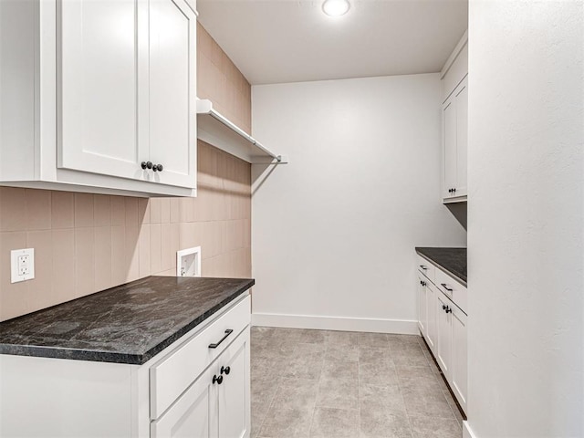 kitchen featuring decorative backsplash, white cabinetry, light tile patterned floors, and dark stone counters