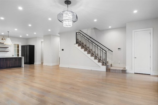 unfurnished living room with a chandelier and light hardwood / wood-style flooring