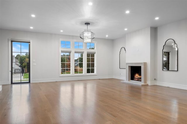 unfurnished living room featuring a healthy amount of sunlight, a notable chandelier, and light hardwood / wood-style floors