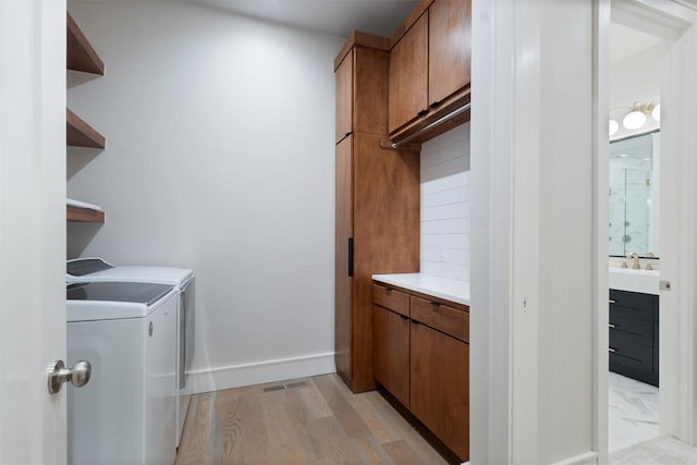 washroom with cabinets, washing machine and dryer, light hardwood / wood-style floors, and sink