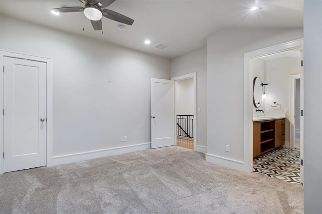 unfurnished bedroom with ceiling fan, light colored carpet, and ensuite bathroom