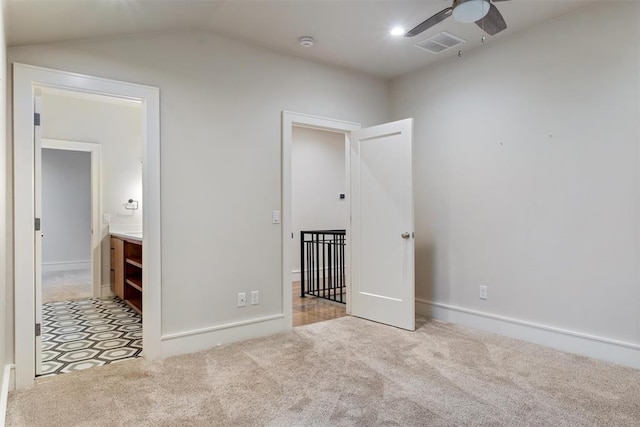 unfurnished bedroom featuring ensuite bath, light carpet, ceiling fan, and lofted ceiling