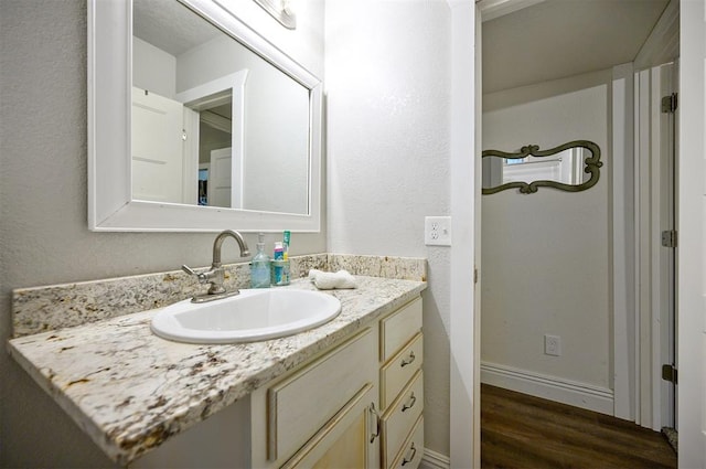 bathroom with baseboards, wood finished floors, and vanity