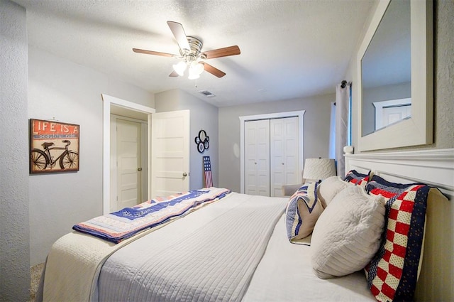 bedroom with a closet, a textured ceiling, visible vents, and a ceiling fan