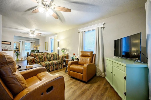living room featuring wood finished floors, a textured ceiling, and ceiling fan