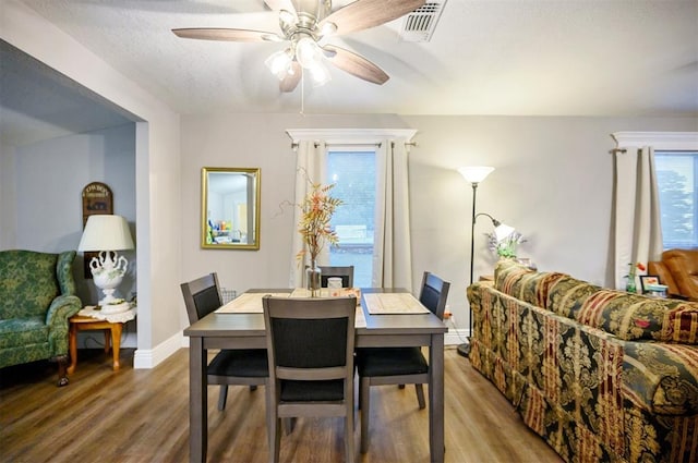 dining space featuring a textured ceiling, baseboards, wood finished floors, and a ceiling fan